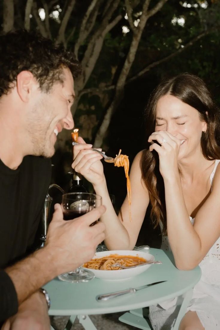 Pareja riendo durante una cita en un restaurante al aire libre